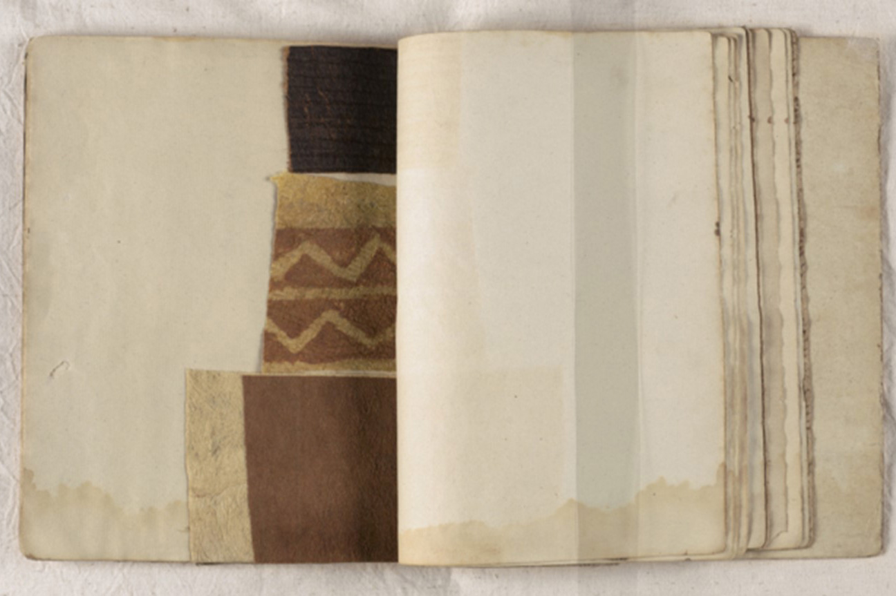 An old water-damaged book with pieces of tapa inserted into it.