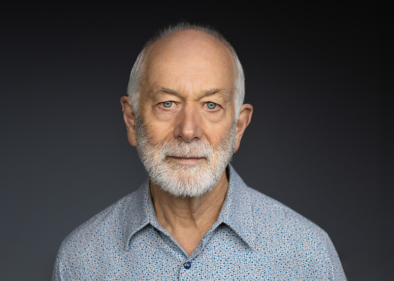 Head and shoulders of a man with a white beard and blue eyes who is looking at the camera.