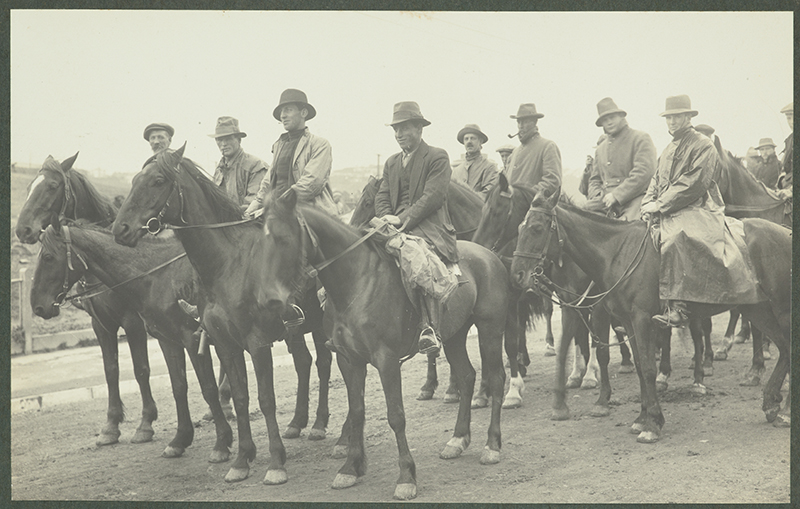 Several men are sitting on horses in a sepia photo.