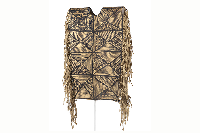 A tapa cloth made into a poncho hanging on a frame.