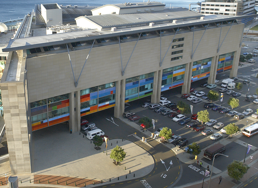The front of the Te Papa museum showing coloured glass panels on one of the walls. In front of it is a carpark.