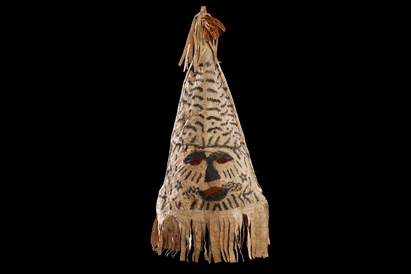 A pointy mask made from a cone of tapa cloth with a face painted on.