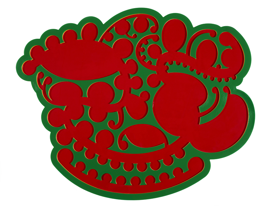 A bright green stamp used for printng a carved shape onto panels. The carved shape has red paint on it from being used to print.