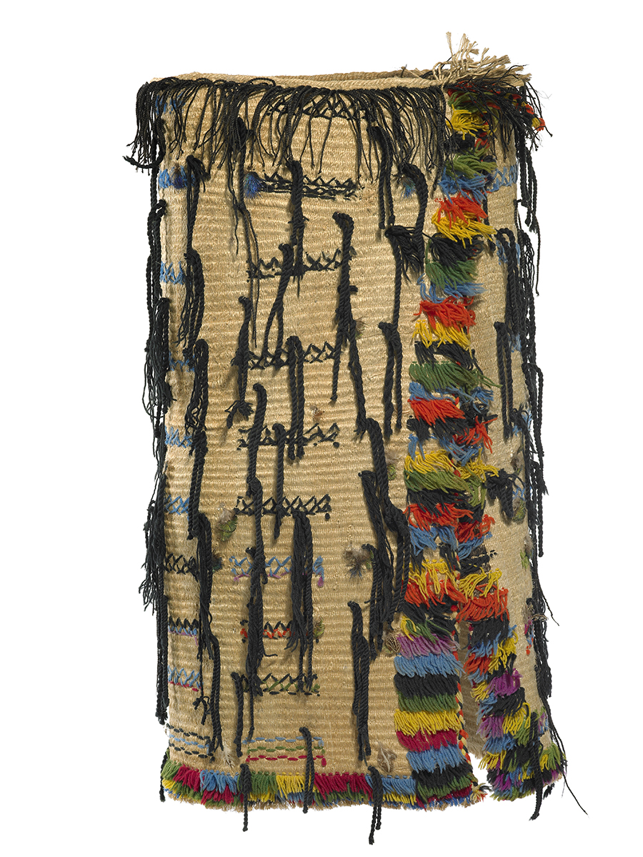 A woven cloak adorned with wool and needlework. Its vibrant, decorative crosses and lines of coloured wool are twined at intervals across the cloak.