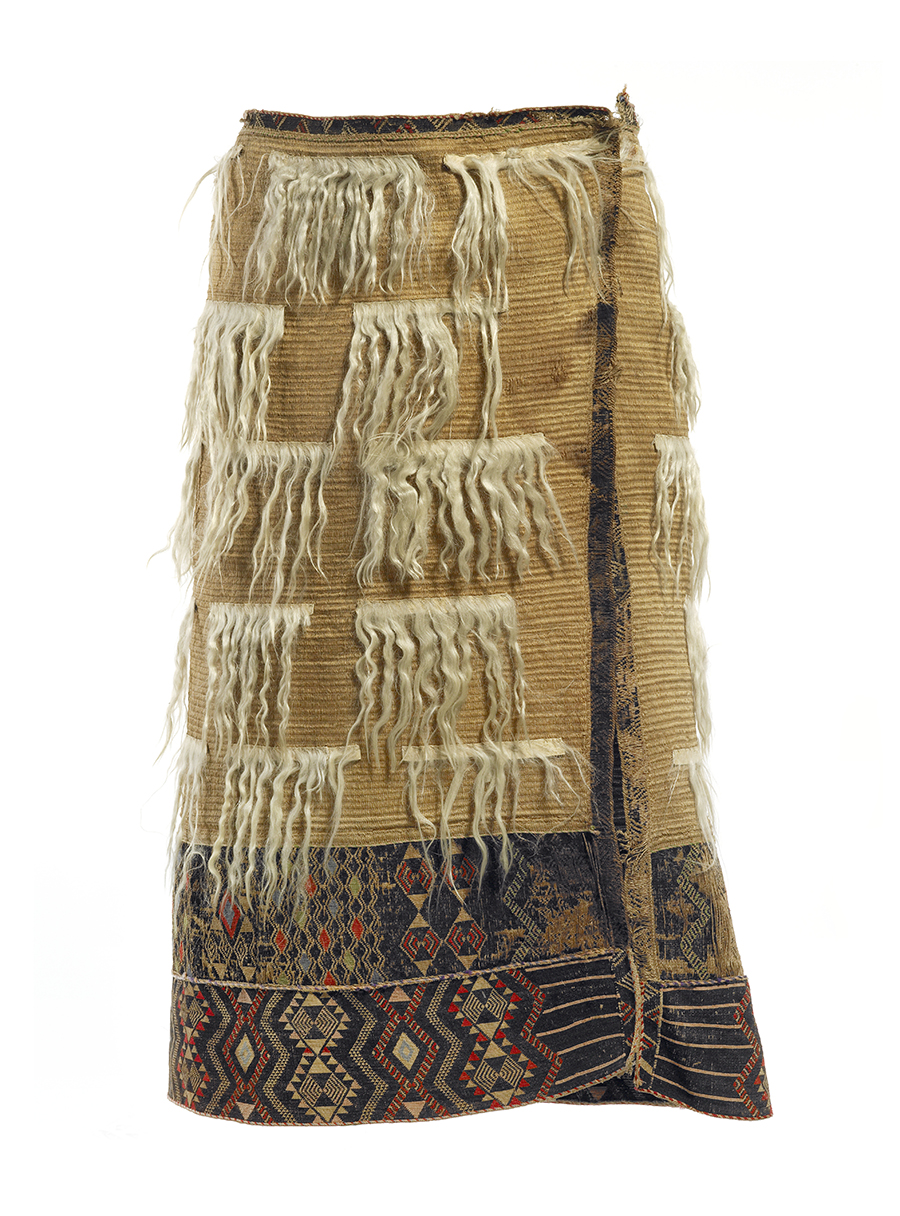 A woven cloak adorned with elaborate borders of tāniko (geometric patterning) and the rows of silken mohair  tied in a set pattern on it.