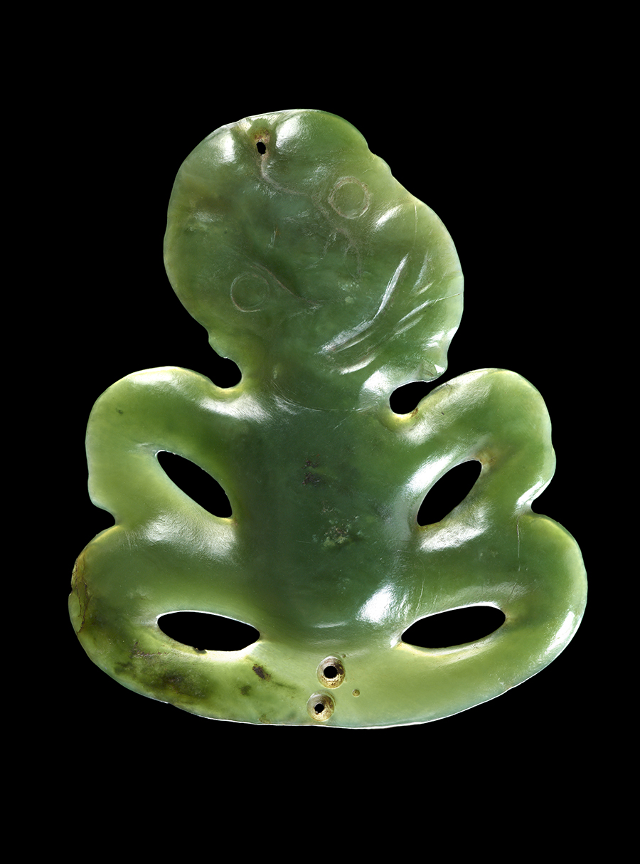 A carved pounamu or greenstone pendant on a black background.