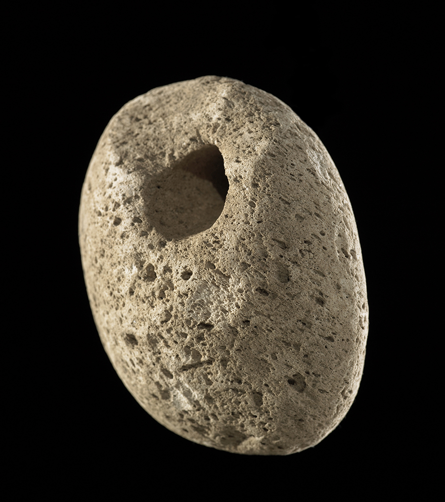 A round stone with a hole in it. The stone is pumice which is light so it will float.