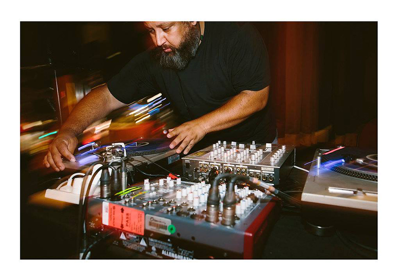 A man with a beard is working a music mixing desk.