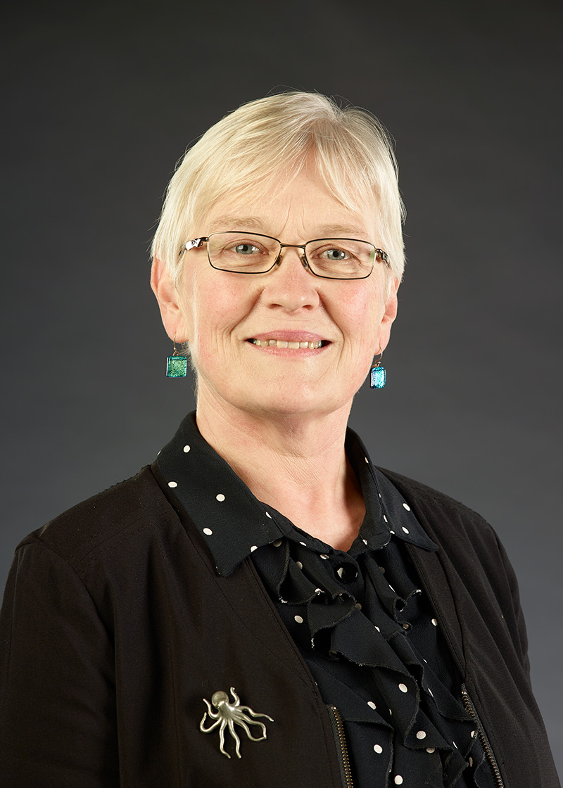 Head and shoulders of a white-haired woman smiling at the camera.