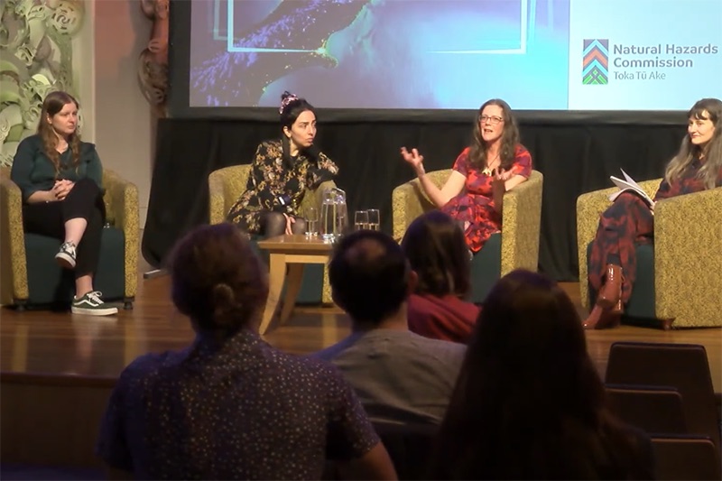 Four women are sitting on a stage and talking to an audience