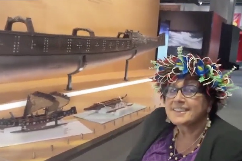 A woman with a flower crown is shown next to a vaka or canoe and two smaller canoe models in a display