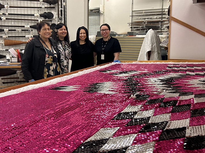 Left to right: Mama Grace Hutton, Emelihter Kihleng, Dr. Dianne Sika-Paotonu, and Melanie Ioane-Warren stand behind the Monomono. Photo by Heather Byrne. Te Papa Four women stand together behind a very pink and sparkly quilt laid out on a drawer