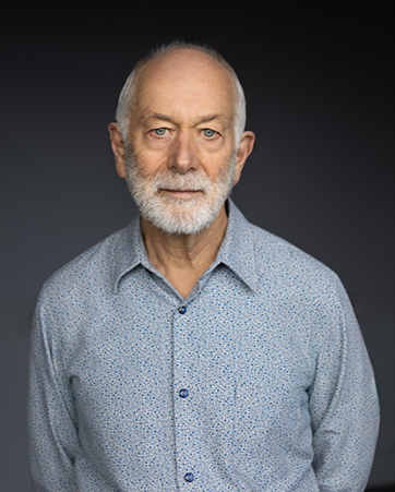 Head and shoulders of a man with a white beard and blue eyes who is looking at the camera.