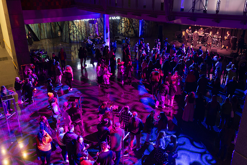 A crowd of people watching a band play on stage.