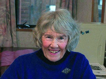 Audrey Eagle An older woman is sitting at a desk with plant illustrations in front of her. She is smiling at the camera.