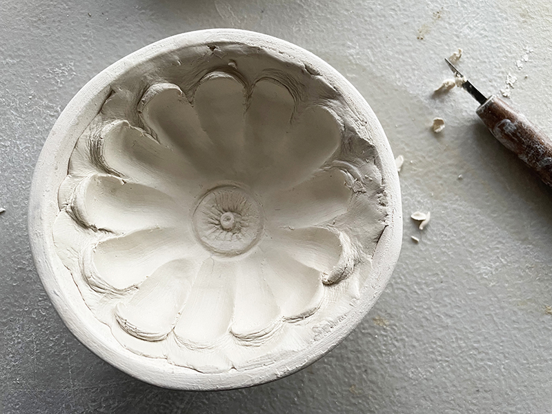 Clay bowl with a hand carved flower in it.