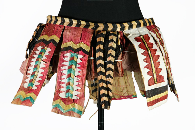 A brightly coloured short skirt or trim to wear over a skirt of strips of tapa and other materials.