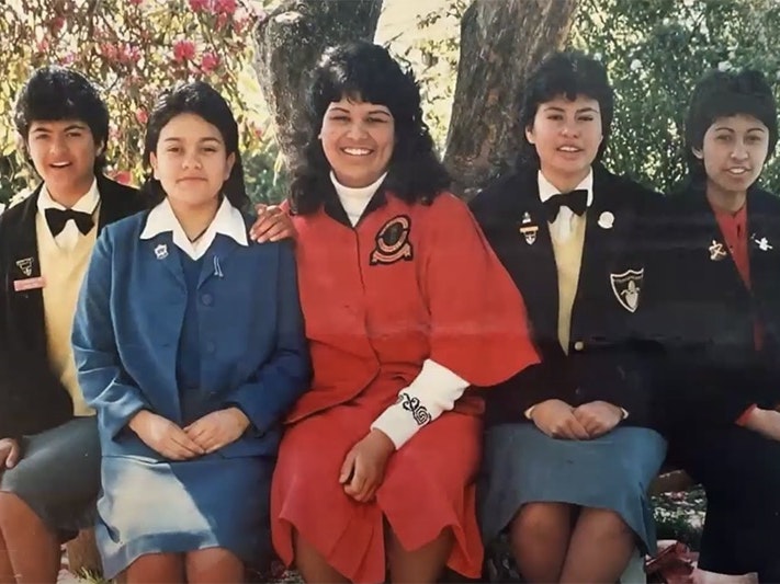 Screenshot from video recording of an online Hui. NSTP Te Papa Five young schoolgirls are sitting under a tree,