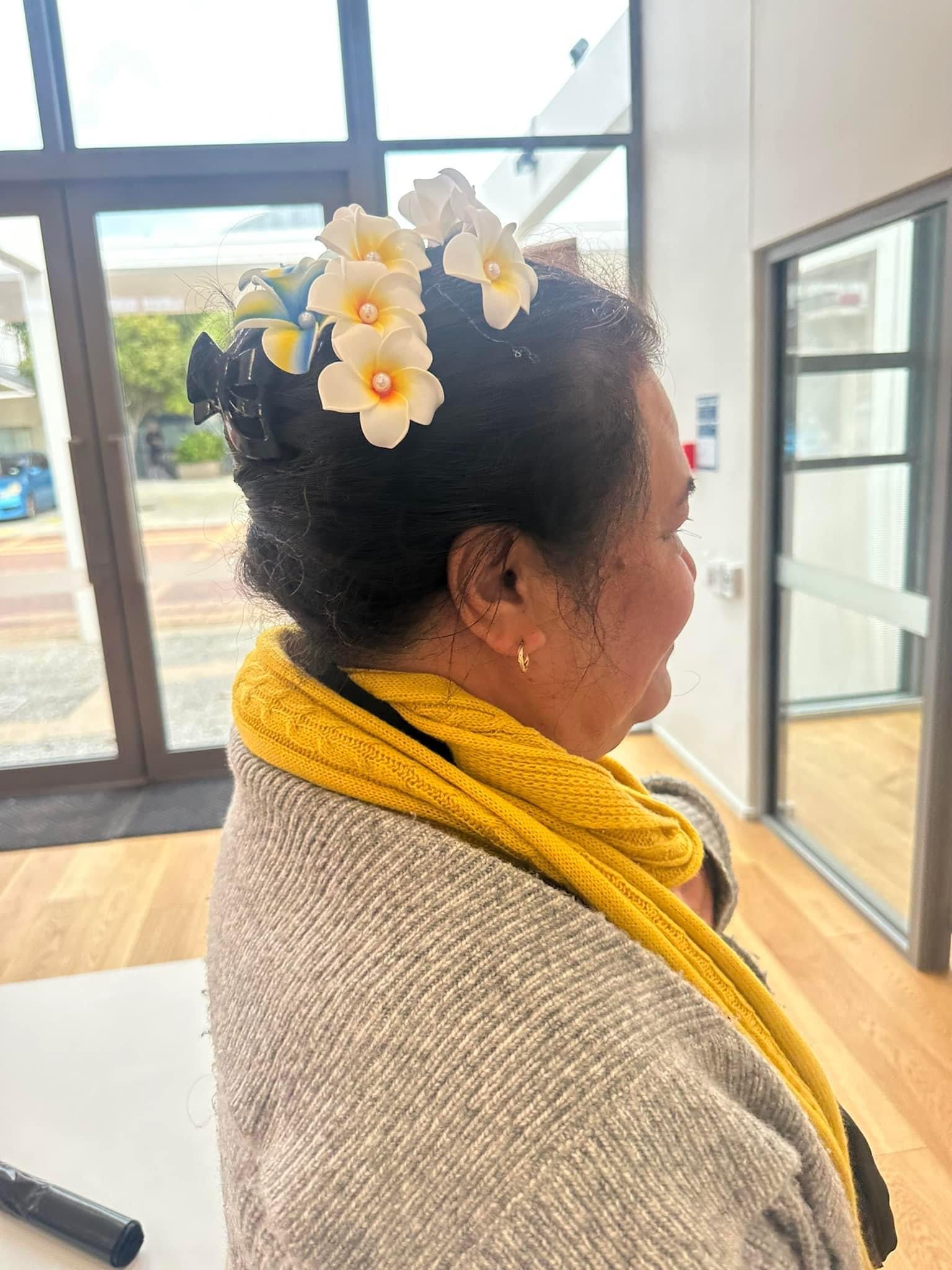 A side view of a woman with a floral clip in her hair.