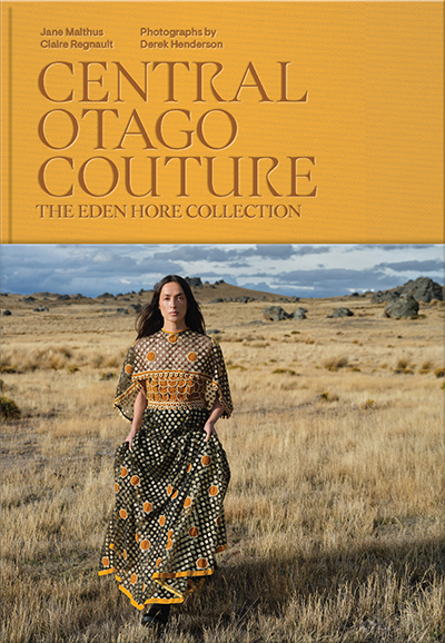 Book cover for Central Otago Couture with the authors, photographer and title in orange and a photo of a woman in a dress standing in a field.