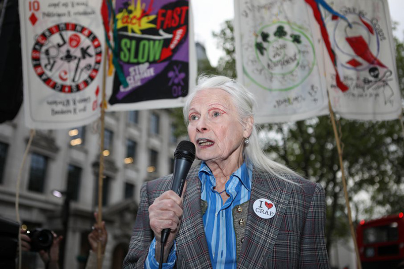 An older woman with long grey hair is speaking through a microphone at a protest march.