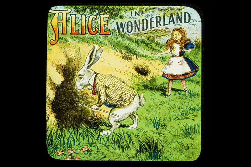 A picture from the Alice in Wonderland with Alice following the white rabbit to a hole in the ground.