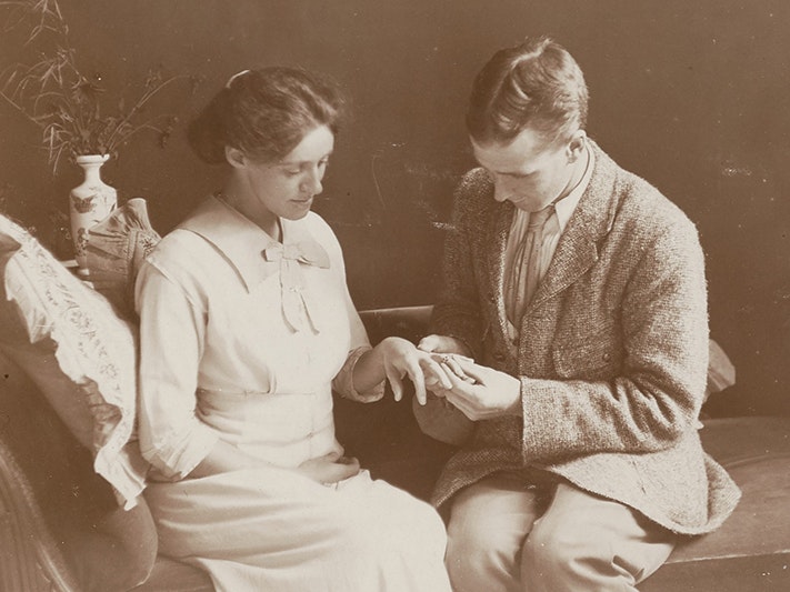 Family photographs, 1913-1914, New Zealand, by Leslie Adkin. Gift of Derek Noble, 1997. CC BY-NC-ND 4.0. Te Papa (AL.000132) Sepia photo of a man putting a ring on a woman.
