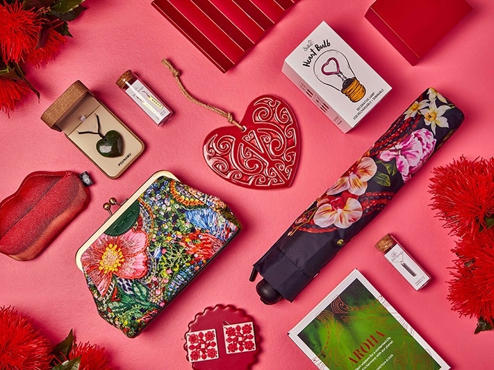 Share the Love, Te Papa Store Collection. Photograph by Nikki Astwood A photo of several objects that are either red or heart-shaped, or lip-shaped all laid out neatly on a pink background.