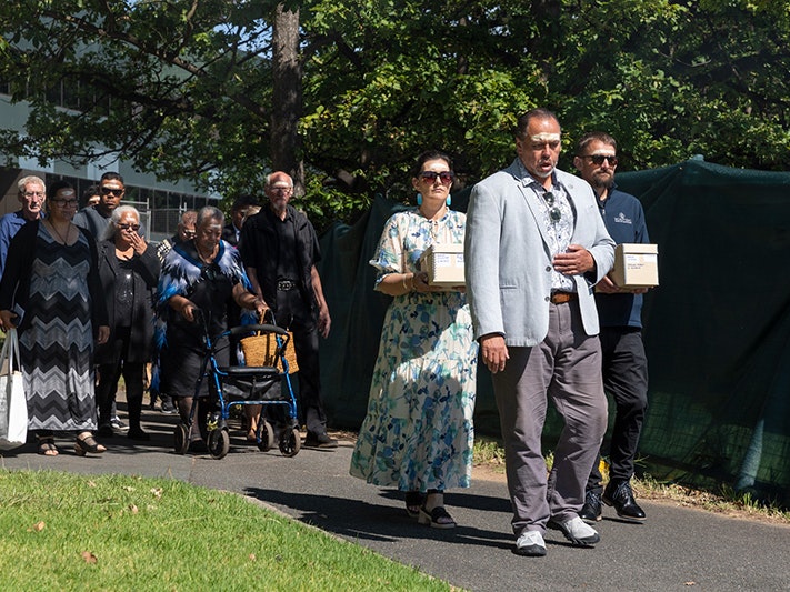 Photo by Jason McCarthy/National Museum of Australia Several people walking along a path. Two are carrying boxes and walking behind the one person in front.