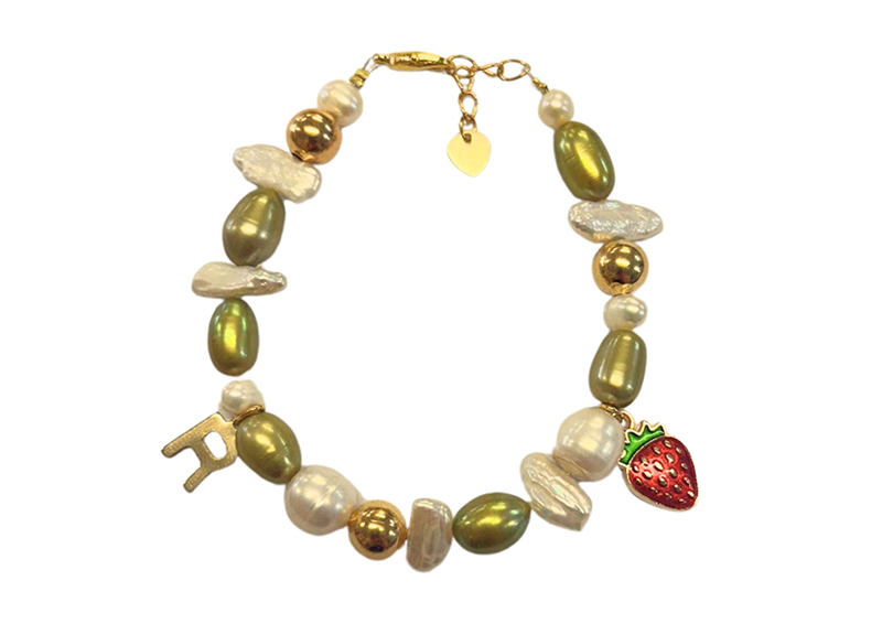 A bracelet with seed pearls and charms with a gold clasp on a white background.