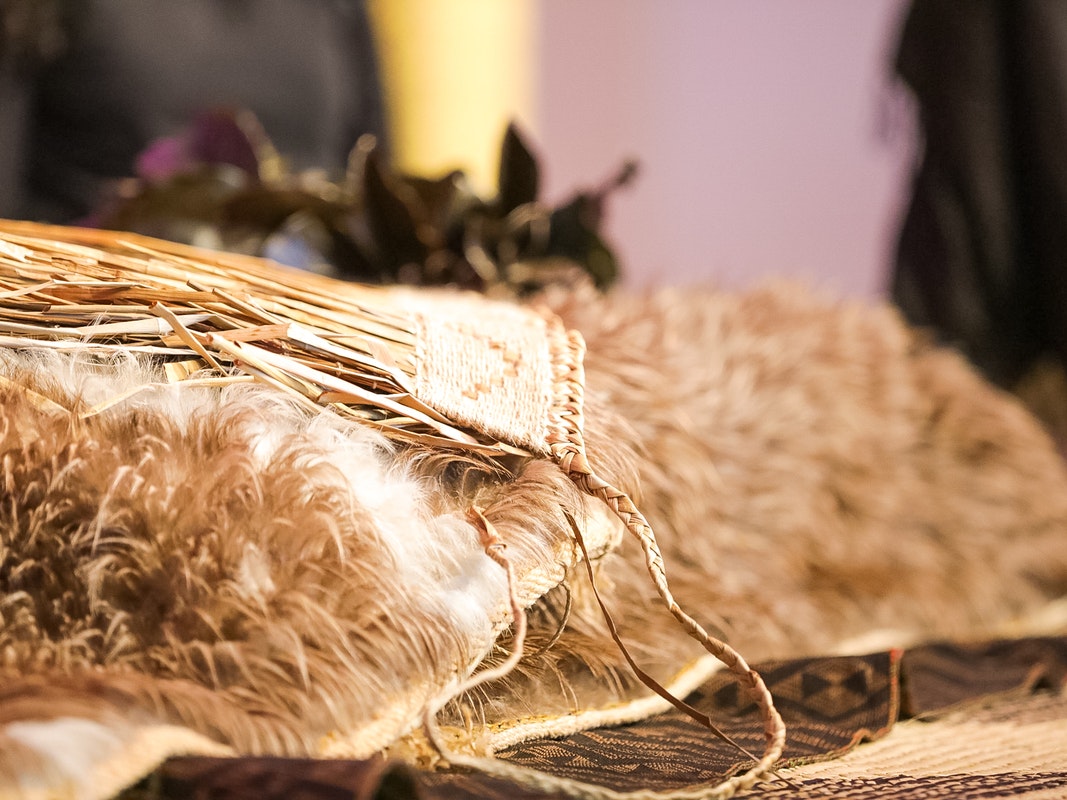 Natural History Museum Vienna Repatriation pōwhiri at Te Papa, 2022. Photo by Abbie Dorrington. Te Papa Kakahu in foreground, with mats underneath and flowers blurred in background