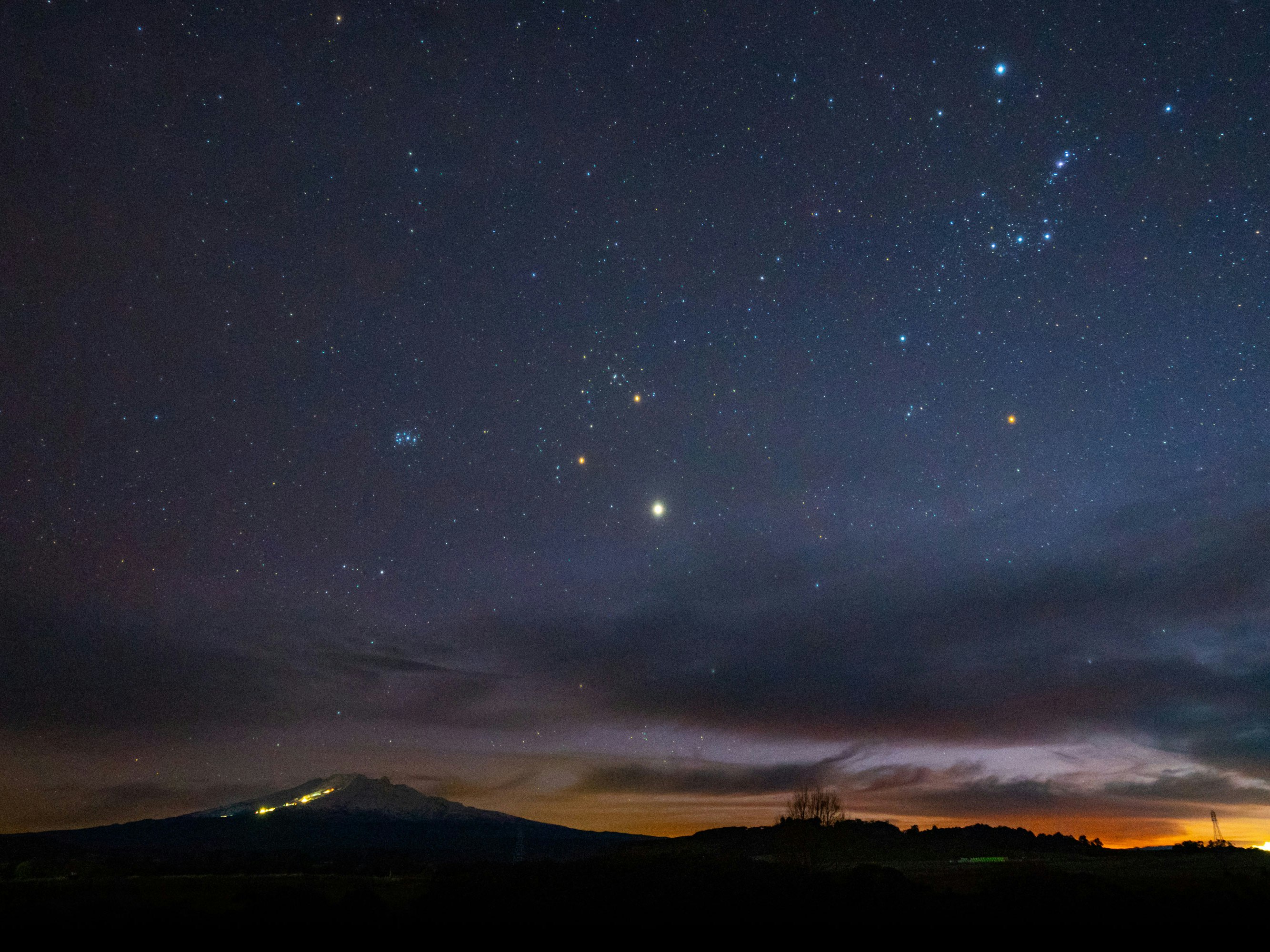 Photo by Mills and NAIA Limited A night sky with stars visible and start of a sunrise.