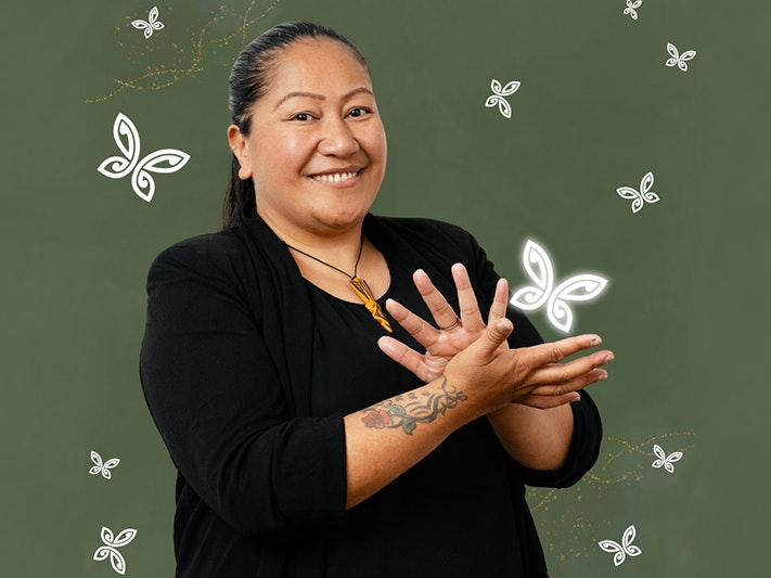 NZSL Awards night. Photo courtesy of NZSL Board A woman is using her hands to say sign language and smiling at the camera.