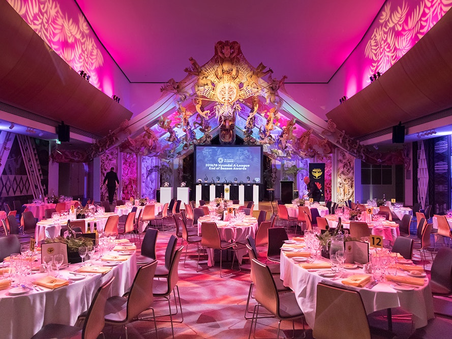 Te Papa Venues, Rongomaraeroa 2019. Photo by Abbie Dorrington. Te Papa (138467) The marae space in Te Papa with pink and purple coloured lighting and tables set up for dinner.