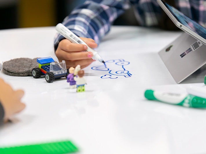 Maraeroa School partaking in Raranga Matihiko. Jo Moore, Te Papa (163572) An image of a child's hand drawing with a marker pen. There is a tablet next to him.