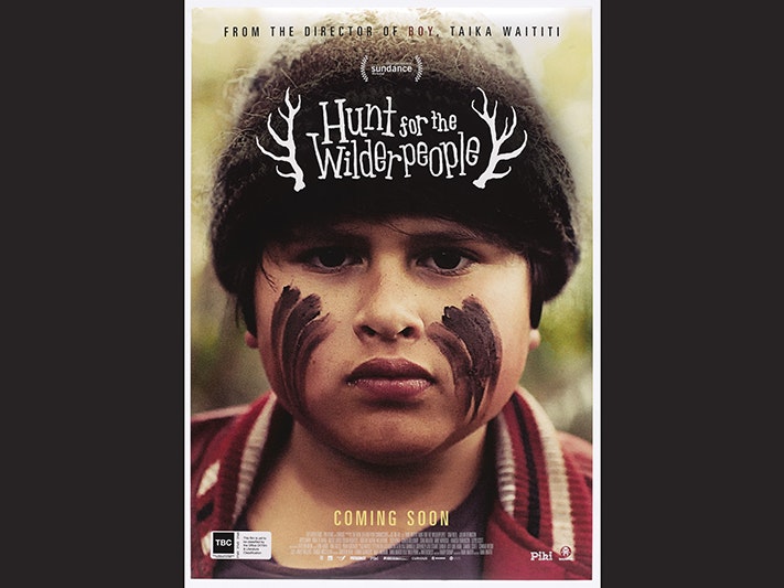 Hunt for the Wilderpeople film poster, Madman Entertainment Pty. Ltd. Gift of Madman Entertainment, 2019. Te Papa (GH025589) A film poster with the title and a close-up shot of Julian Denniston with markings on his face and a woolly hat.