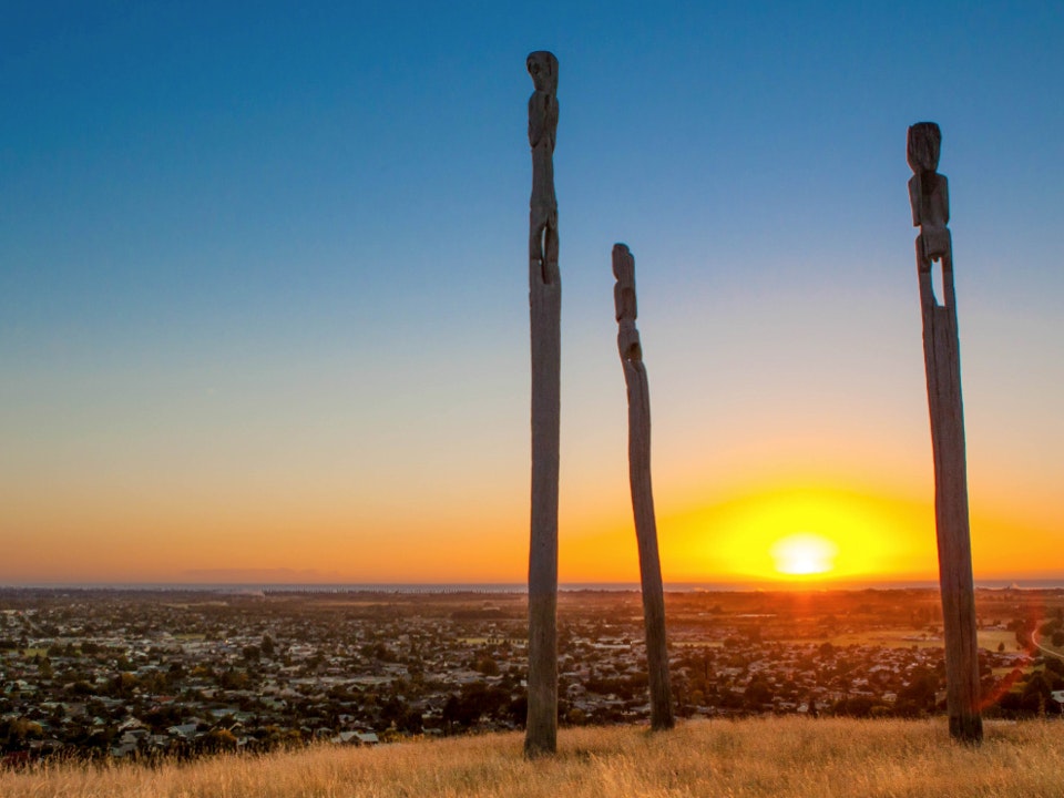 Tūhonohono graphic Three pou or poles standing on the top of a mountain at sunrise.