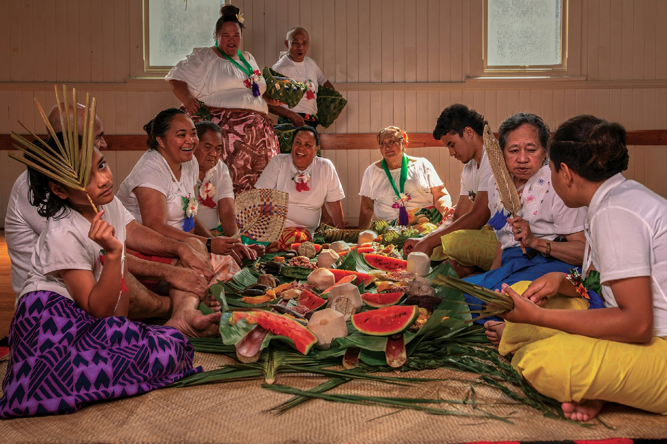Rotuma Language Week story tile. Photo from Ministry of Pacific Peoples People sitting around a feast on a woven mat.