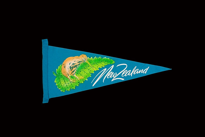 Souvenir pennant, 'New Zealand', Unknown; manufacturer(s); 1970s-1980s; New Zealand. Gift of Alan Tennyson, 2009. Te Papa (GH020755) A blue triangular pennant felt flag with the words New Zealand on it, and a kiwi on top of a fern.