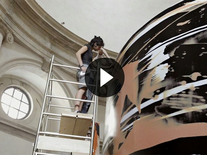 Still from video about installing Judy Millar's exhibiton at Venice Biennale, 2009. Two people are on some scaffolding installing a giant artwork in an old building.