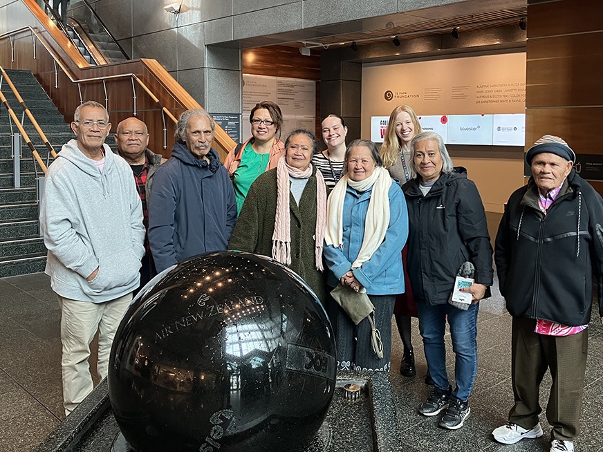 Omai Fa’atasi kaumātua visiting Te Papa. Photo by Vanessa Lavatai from Age Concern Ten people standing behind the large stone ball in the foyer of Te Papa. They are all smiling at the camera.