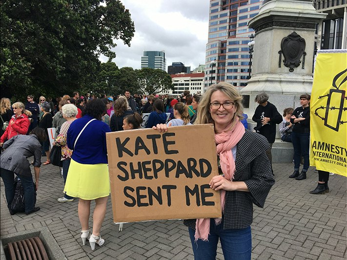 Kate Sheppard Sent Me placard held by Leah McFall at the Women's March on Washington in Wellington, 21 January 2017, Wellington, by Jane O'Loughlin. Gift of Leah McFall, 2017. © Te Papa. CC BY-NC-ND 4.0. Te Papa (O.045209) A woman is outside parliament and holding a sign saying "Kate Sheppard sent me"